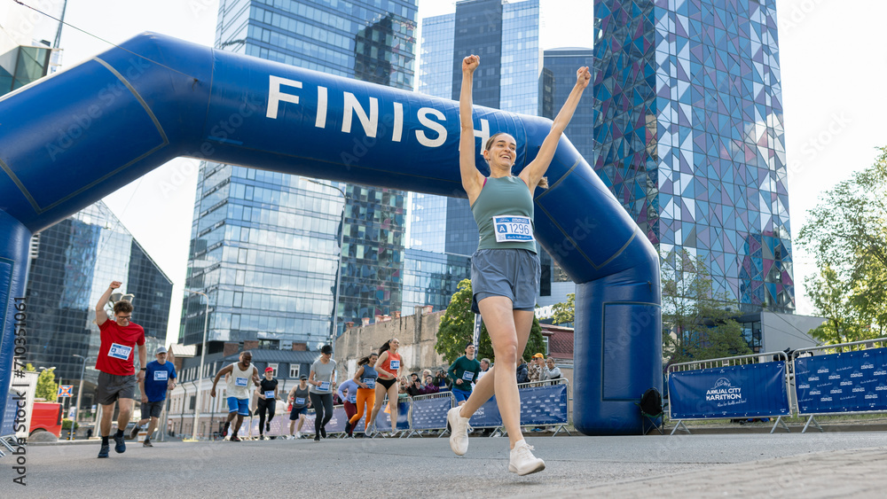 Portrait of Happy Female Runner Participating in a Marathon. Athletic Female Crossing the Finish Line, Celebrating, Raising Hands in the Air